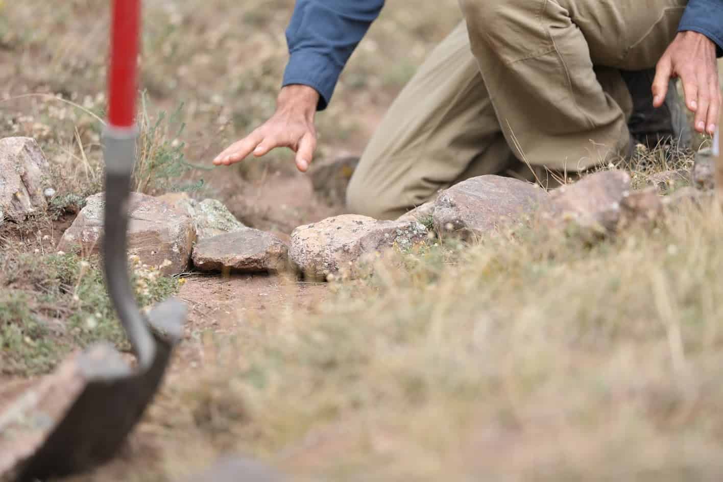 Manos colocando a mano las piedras de un dique en la ladera.